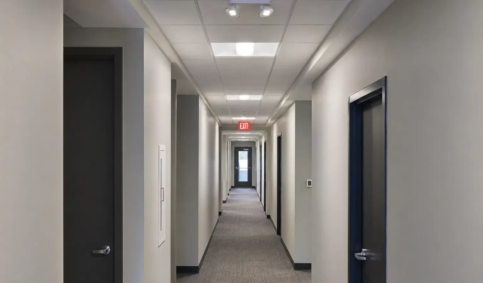 Commercial corridor with emergency lighting and illuminated exit sign